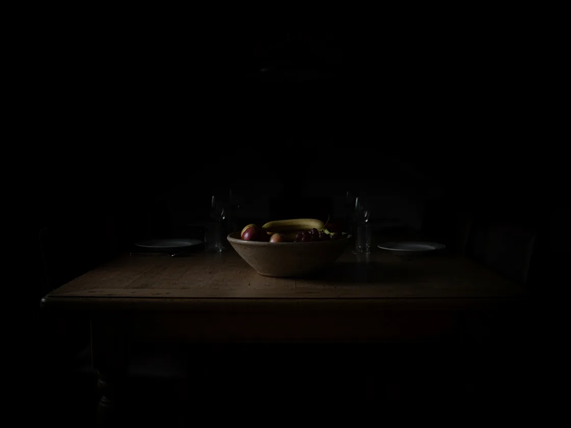 A severely underexposed photo of a dining table, almost entirely lost in deep shadow.